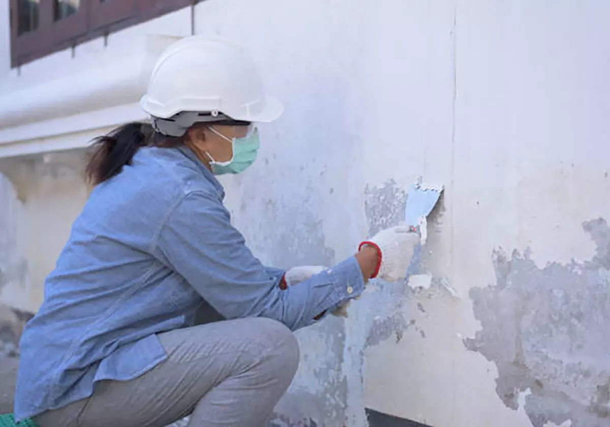 Mulher restaurando parede com espátula